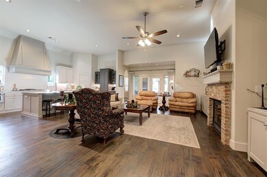 Living room with a brick fireplace, a ceiling fan, dark wood-style floors, healthy amount of natural light, and recessed lighting