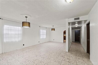 Unfurnished room with arched walkways, a textured ceiling, visible vents, and light floors