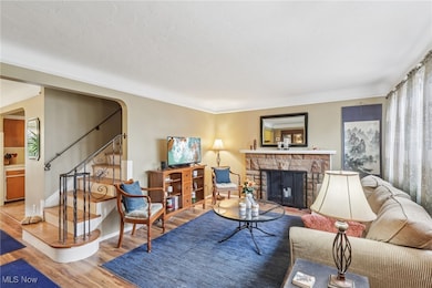 Living area with stairway, wood finished floors, a stone fireplace, and arched walkways