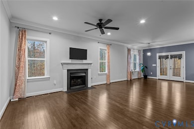 Unfurnished living room featuring crown molding, dark wood-style floors, a fireplace with flush hearth, ceiling fan, and recessed lighting