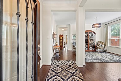 This is an elegant entryway leading into a well-lit, spacious living area with hardwood floors, tasteful decor, and large windows that bring in natural light.