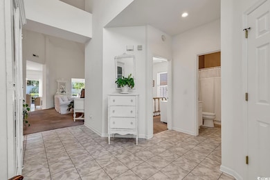 Bathroom featuring toilet, recessed lighting, tile patterned floors, baseboards, and a towering ceiling