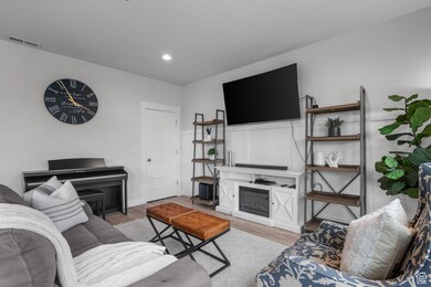 Living area featuring light wood-style floors, a glass covered fireplace, and recessed lighting