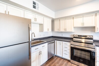 Kitchen with visible vents, a sink, dark countertops, wood finished floors, and stainless steel appliances