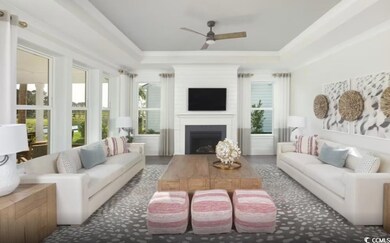 Living area featuring a raised ceiling, a ceiling fan, a fireplace, and ornamental molding