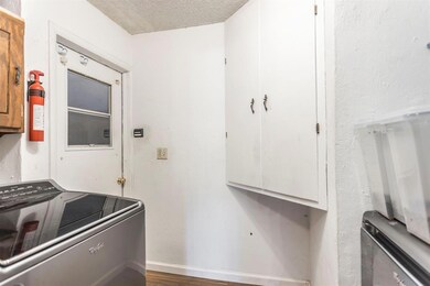 Washroom featuring washer / dryer, cabinet space, a textured ceiling, and wood finished floors