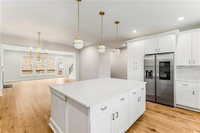 A closer view of the enormous quartz center island, bright white cabinetry, custom backsplash & custom pendant lighting. Custom light fixtures run throughout this entire luxury home.