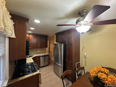 Kitchen with light tile patterned floors, tasteful backsplash, black appliances, recessed lighting, and dark brown cabinets