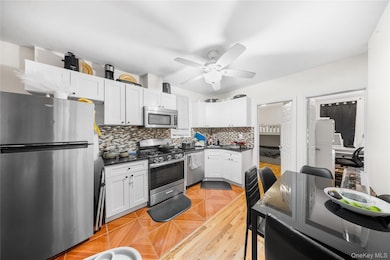 Kitchen with appliances with stainless steel finishes, decorative backsplash, and white cabinets