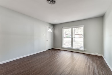 Empty room featuring baseboards and dark wood finished floors