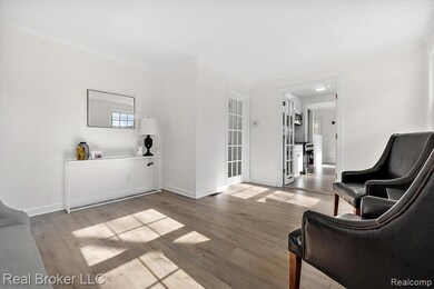 Sitting room with crown molding and light wood-style floors