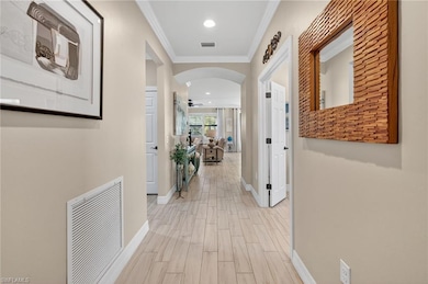 Corridor featuring arched walkways, ornamental molding, wood tiled floors, and recessed lighting