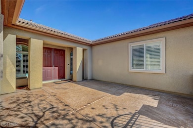 Entrance to property featuring a tiled roof, a patio area, and stucco siding