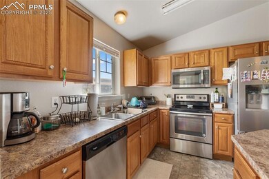Kitchen with appliances with stainless steel finishes, lofted ceiling, and brown cabinetry