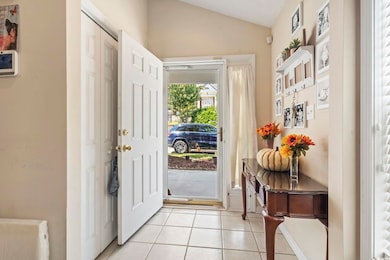 Entryway with light tile patterned flooring and lofted ceiling