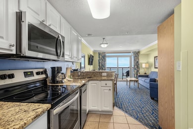 Kitchen featuring stone counters, white cabinets, 