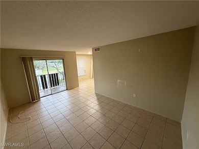 Unfurnished room featuring light tile patterned floors and a textured ceiling