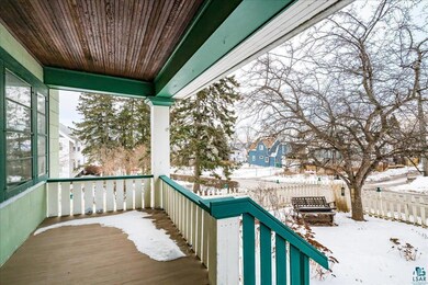 Snow covered back of property with a porch