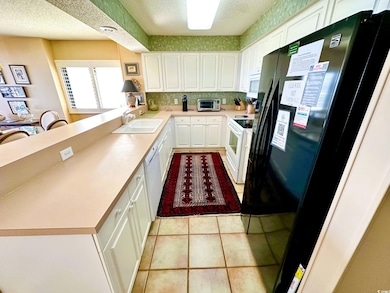 Kitchen featuring white cabinetry, sink, white app
