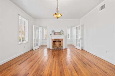 Unfurnished living room featuring wood-type flooring, a fireplace, baseboards, and crown molding