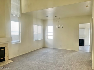 Unfurnished living room featuring light carpet, a tile fireplace, and a chandelier
