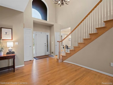 Foyer entrance featuring light wood-style floors, a high ceiling, a chandelier, and stairs