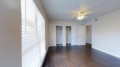 Unfurnished bedroom with two closets, dark wood-type flooring, and a ceiling fan