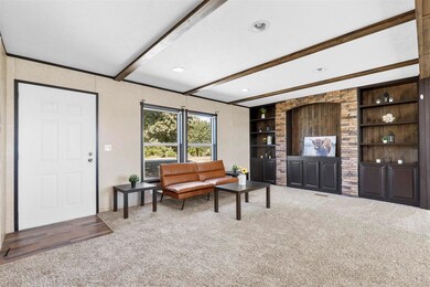 Carpeted living room featuring beam ceiling, a tex