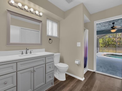 Updated poolside bathroom with direct lanai access, modern vanity, luxury vinyl flooring, and private shower—perfect for post-swim convenience.