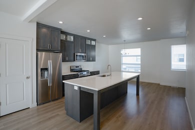 Kitchen featuring stainless steel appliances, glass insert cabinets, an island with sink, a breakfast bar area, and light wood-type flooring