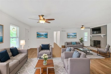 Living area with a ceiling fan, wood finished floors, a fireplace, and crown molding