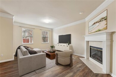 Living room with crown molding, wood finished floors, baseboards, and a fireplace