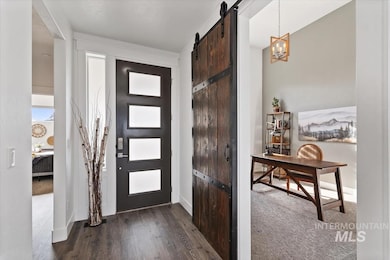 Entryway with a barn door, dark wood-type flooring, dark colored carpet, and a chandelier