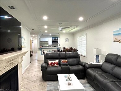 Living room with a ceiling fan, light tile patterned floors, a fireplace, recessed lighting, and ornamental molding