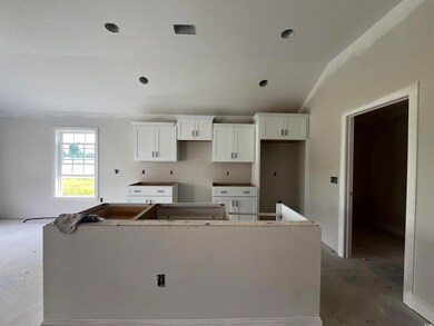 Kitchen featuring a kitchen island, lofted ceiling, white cabinets, and concrete flooring