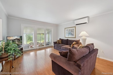 Living room with light wood-type flooring, crown molding, and a wall mounted air conditioner