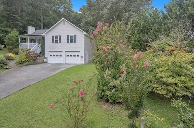 View of front of property featuring driveway, a chimney, a porch, a garage, and a front yard