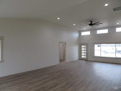 Spare room featuring wood finished floors, ceiling fan, recessed lighting, and a towering ceiling