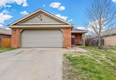 Front of home with concrete driveway, brick siding, an attached garage, and fence