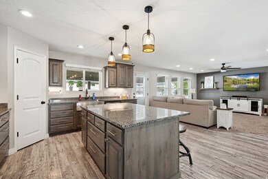 Kitchen with hanging light fixtures, a kitchen breakfast bar, recessed lighting, dark stone counters, and open floor plan