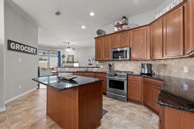 A chef's delight! This kitchen features a breakfast bar alongside elegant wood cabinets and granite, all while offering an open view into the living areas.