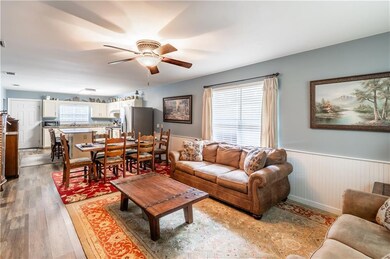 Living area with ceiling fan, wainscoting, and wood finished floors