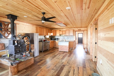 Kitchen with wooden ceiling, wooden walls, hardwood / wood-style floors, a wood stove, and range with two ovens
