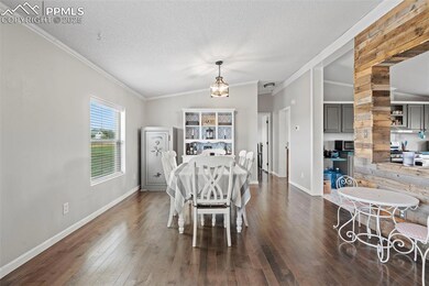 Dining area with ornamental molding, dark wood-type flooring, and a textured ceiling
