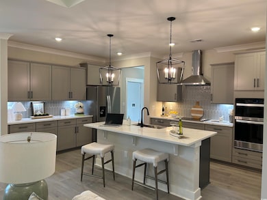 Kitchen featuring gray cabinetry, a breakfast bar, backsplash, wall chimney exhaust hood, and crown molding