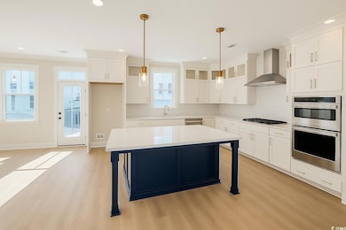 Kitchen with wall chimney exhaust hood, a breakfast bar area, backsplash, stainless steel appliances, and crown molding