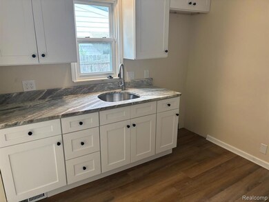 Kitchen with white cabinets, granite counters, and dark wood-style flooring
