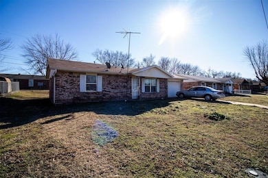 Ranch-style home with a garage, brick siding, and a front lawn