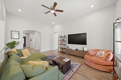 Inviting living room highlighting the high ceilings, recessed lighting, and a clear sightline towards the front entry and main hallway.