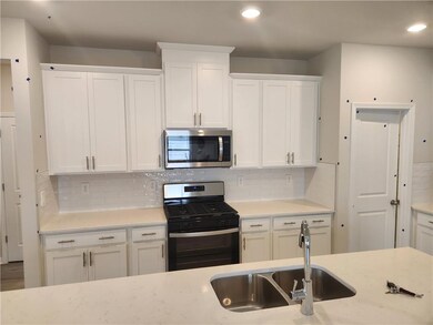 Kitchen with appliances with stainless steel finishes, white cabinets, backsplash, and light stone countertops